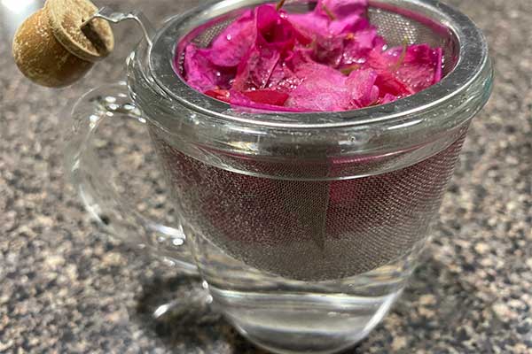 Picture of Bougainvillea bracts in a mesh strainer soaking in hot water.